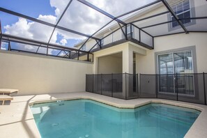 Une piscine intérieure dotée d’un toit en verre, d’un patio couvert et offrant une vue sur le ciel.