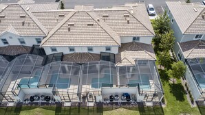 A residential building with a swimming pool, multiple balconies, and a car parked nearby.