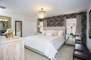 Une chambre à coucher avec un grand lit, une commode, une coiffeuse avec un miroir et un lustre.