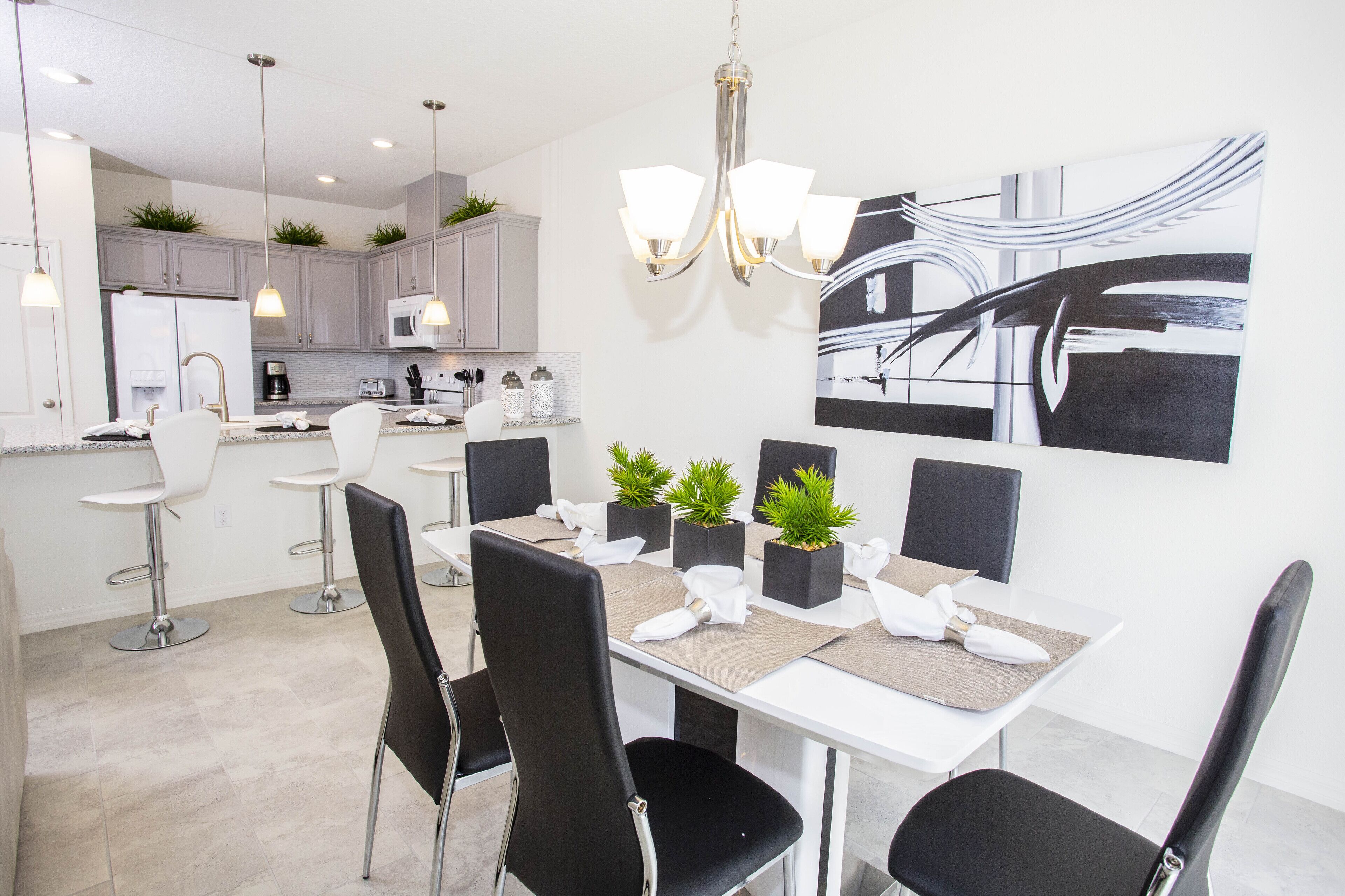 A modern kitchen with white cabinets, a central island, and pendant lighting.