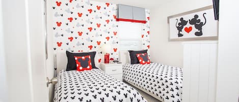 Ein Schlafzimmer mit zwei Betten, beide mit Bettwäsche im Mickey-Mouse-Design.
