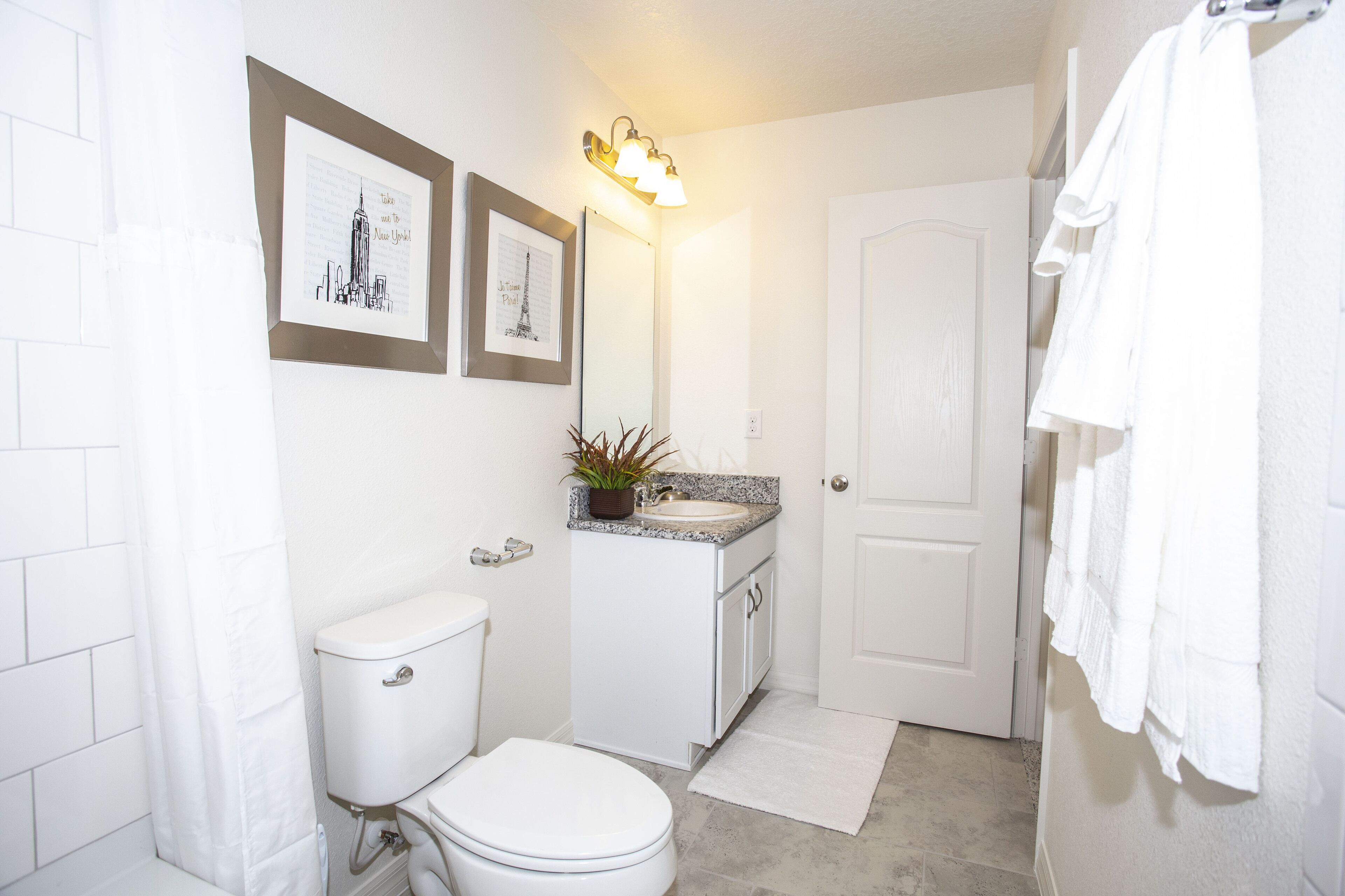 A bathroom with a toilet, sink, and a mirror with framed pictures.