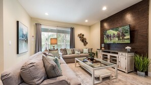 A living room with a sofa, coffee table, TV, and decorative items. - Wonderful 8Bd w/ Pool & GameRoom @ Encore 461 (Kissimmee)