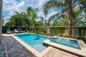 A rectangular swimming pool with a tiled edge, surrounded by a brick patio. There are lounge chairs and a small table near the pool. - Wonderful 8Bd w/ Pool & GameRoom @ Encore 461 (Kissimmee)