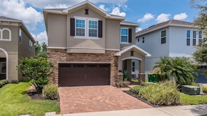 A two-story house with a brick driveway and a stone facade. - Wonderful 8Bd w/ Pool & GameRoom @ Encore 461 (Kissimmee)