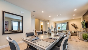 A spacious dining area with a long table, multiple chairs, and a large mirror on the wall. - Wonderful 8Bd w/ Pool & GameRoom @ Encore 461 (Kissimmee)