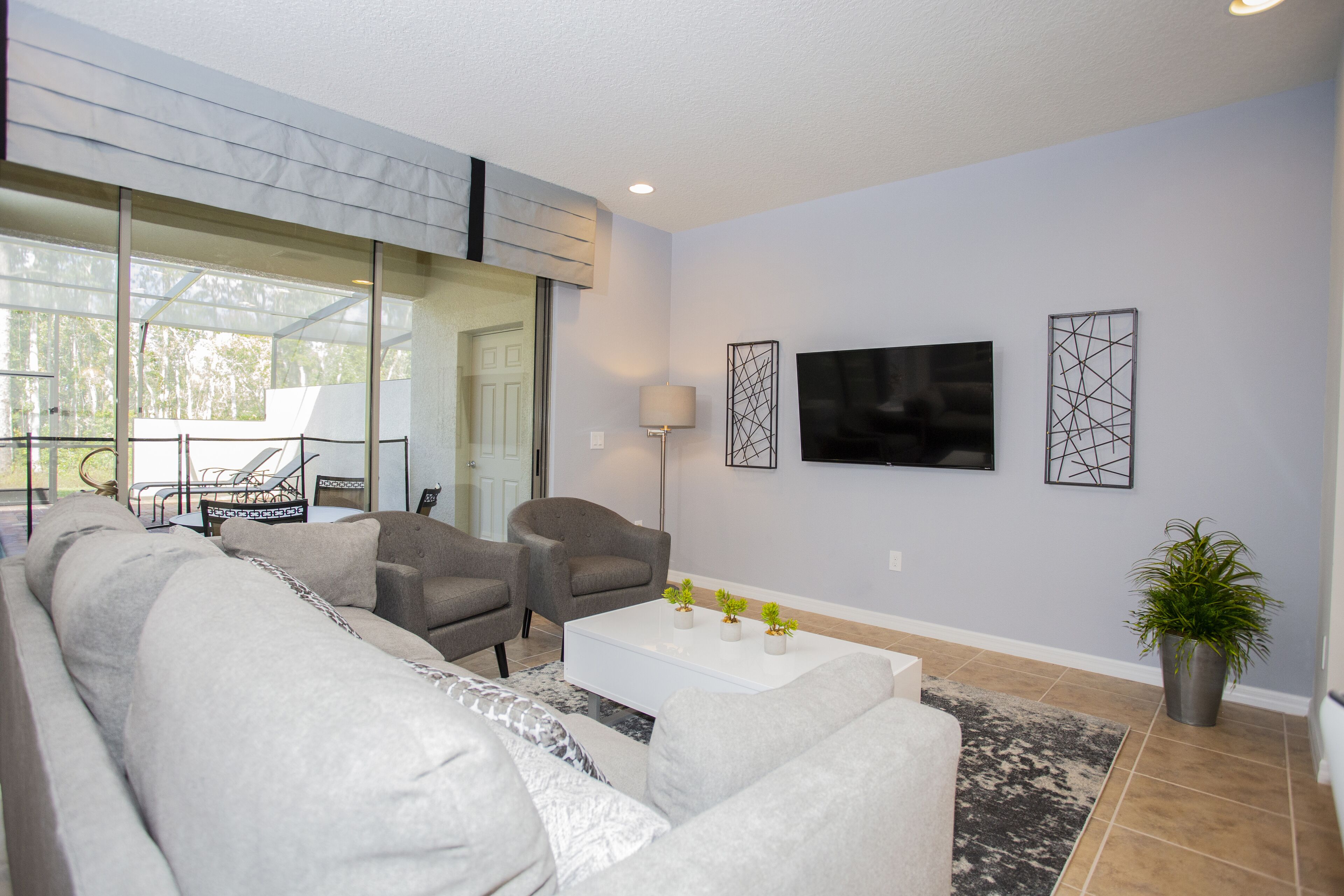 A modern living room with a sofa, armchairs, a coffee table, and a TV mounted on the wall.