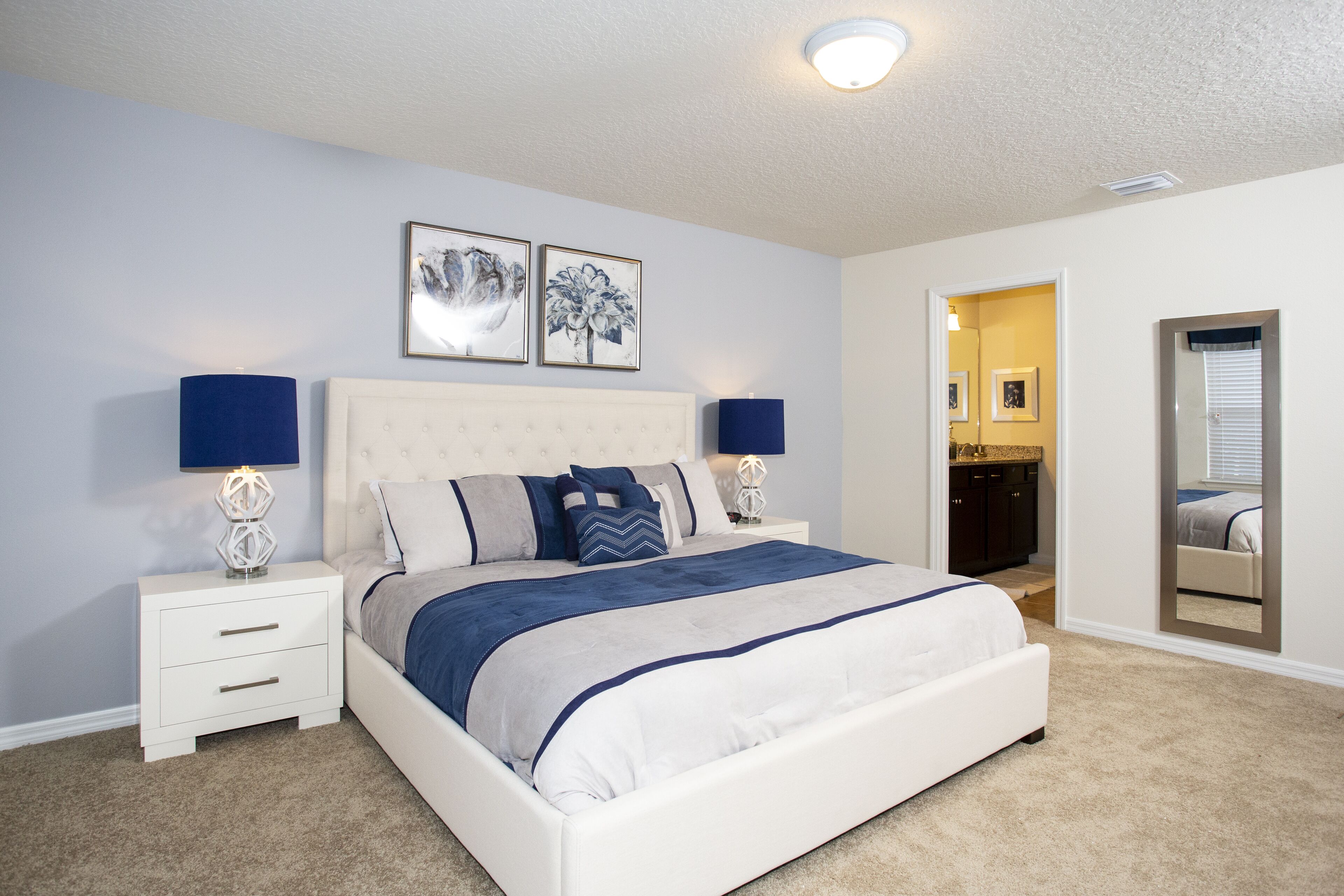 A bedroom with a bed, nightstands, and a mirror.