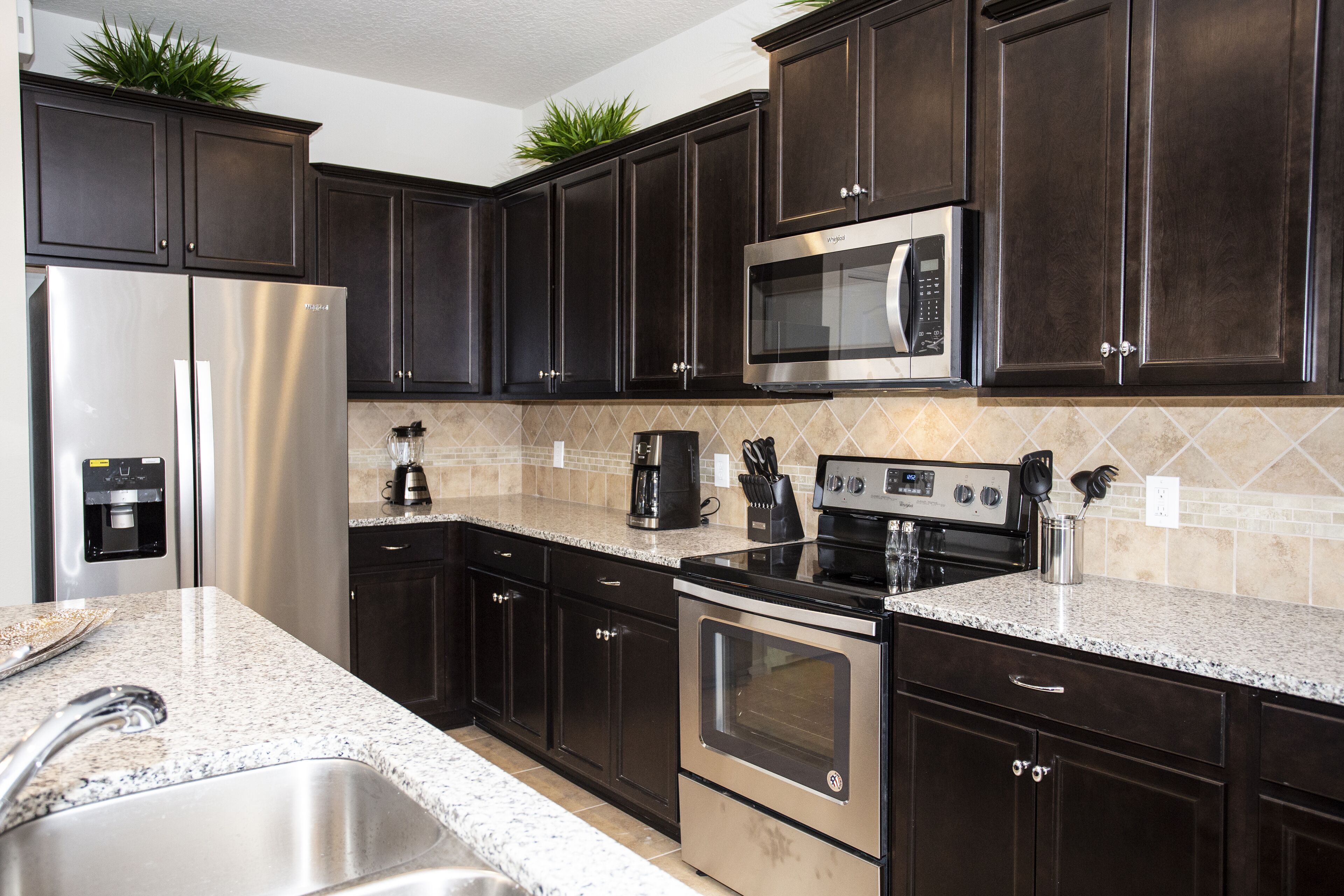 A modern kitchen with dark cabinets, stainless steel appliances, and a granite countertop.