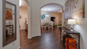Un amplio salón con mesa de comedor, sillas y televisor al fondo.