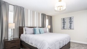 A bedroom with a large bed, two bedside tables, a nightstand, and a ceiling light fixture.