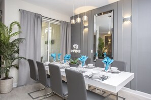 A modern dining room with a white table set for six, grey chairs, and a large mirror on the wall.