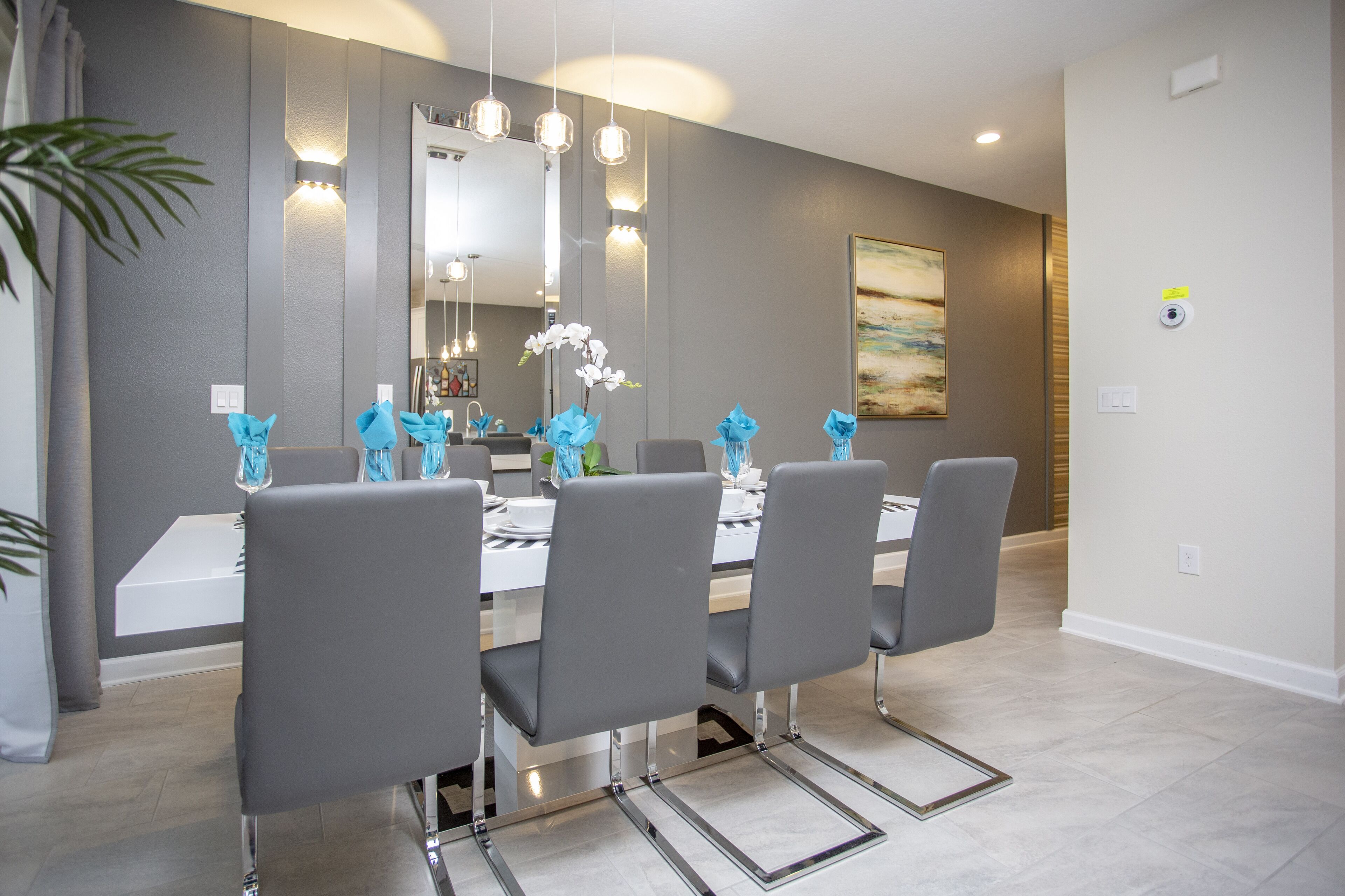 Un comedor moderno con una mesa blanca, sillas grises y flores azules decorativas.