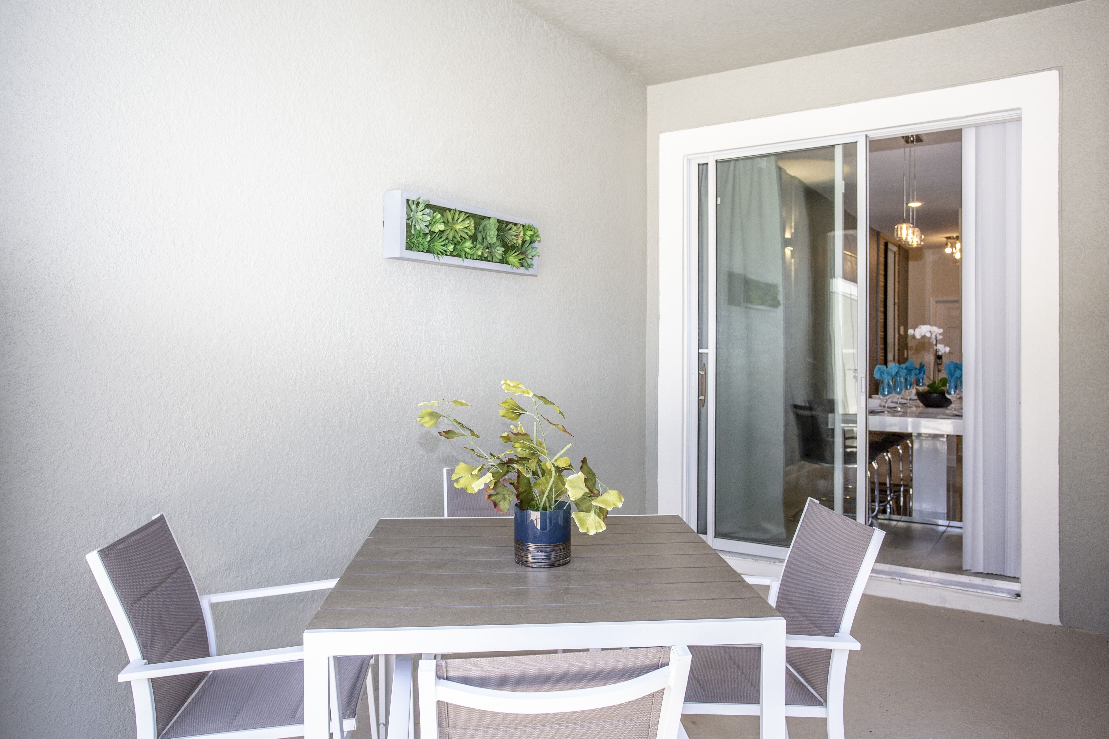 A dining area with a table and chairs, a potted plant, and a sliding glass door leading to a balcony.