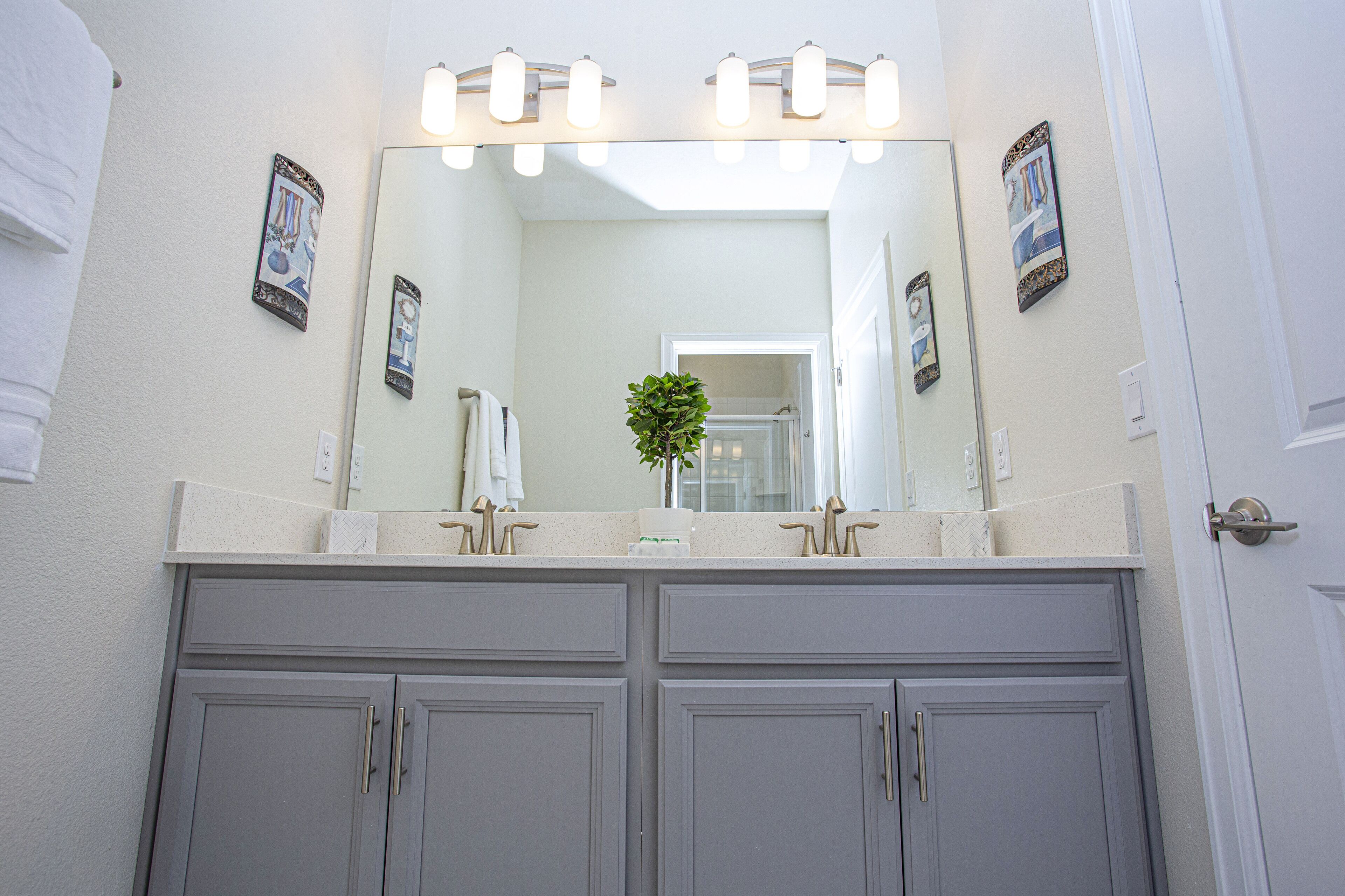A bathroom with a double vanity, a large mirror, and wall-mounted lights.
