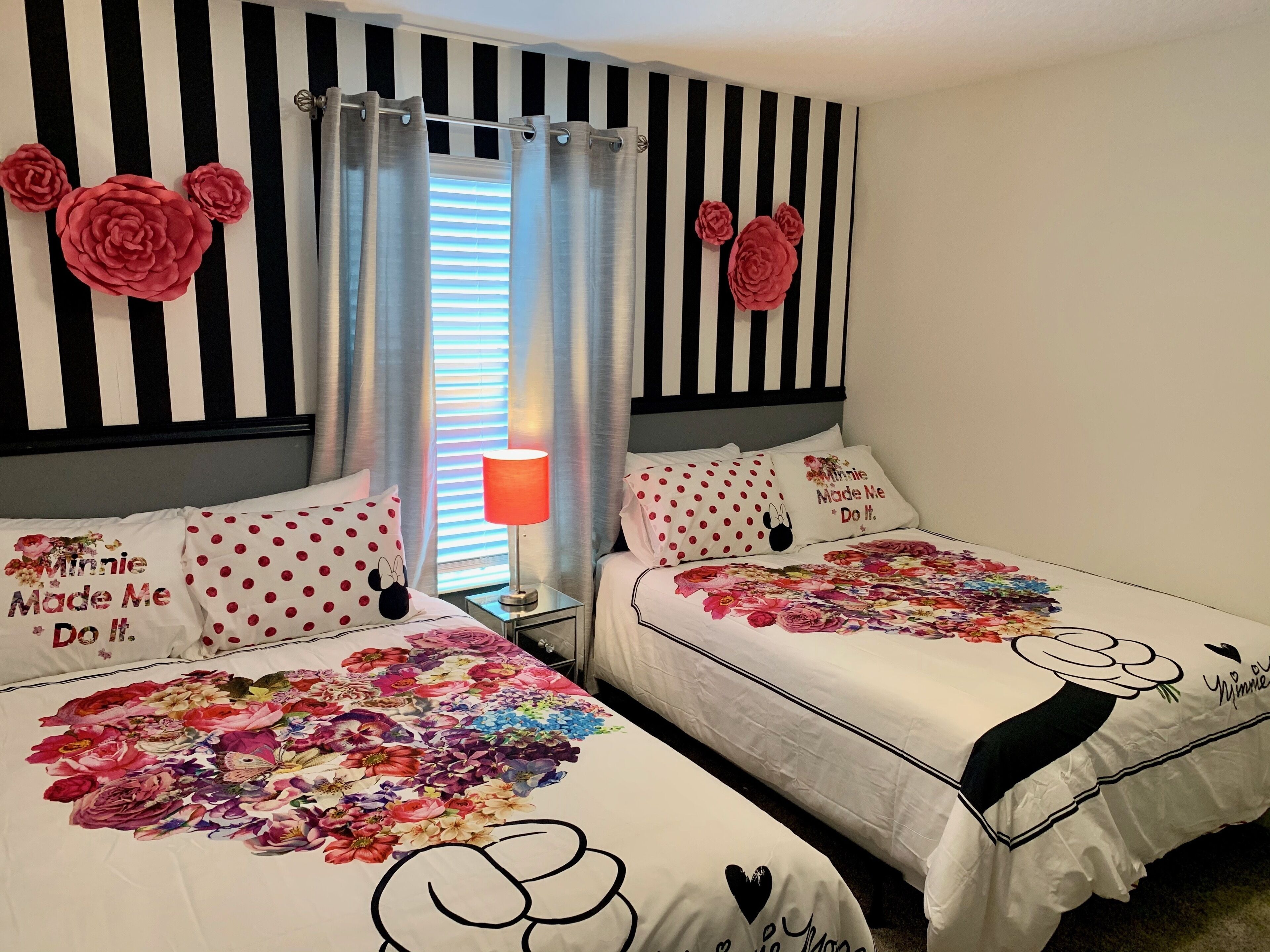 Une chambre avec deux lits, des murs à rayures et des couvre-lits à motifs floraux.