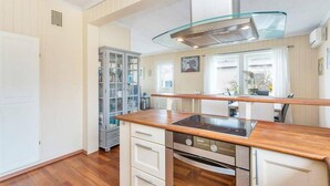 A modern kitchen with a glass hood, wooden countertop, and built-in cabinetry.