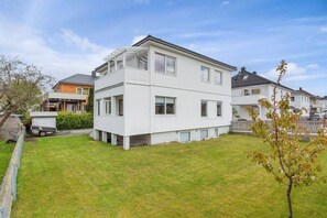 A two-story residential building with a flat roof, large windows, and a small front yard. - StayPlus 3BR City Apartment With Garden (Kristiansand)