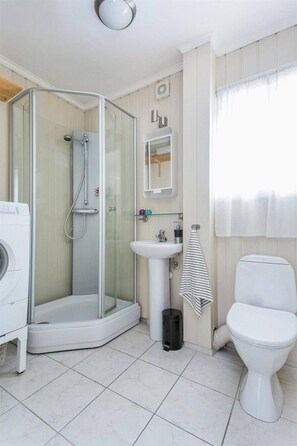 A modern bathroom with a glass-enclosed shower, a white sink, and a toilet. - StayPlus 3BR City Apartment With Garden (Kristiansand)