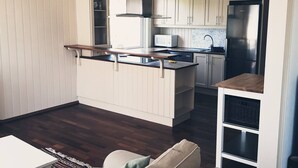 A modern kitchen with white cabinets, a stainless steel refrigerator, and a microwave.