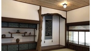 A traditional Japanese room with tatami flooring, a wooden shelf with decorative items, a hanging scroll, and a window with a lattice design. - A 100-year-old folk house has been completely renewed, and you can enjoy living in a satoyama in just one hour from the Tokyo metropolitan area via the Aqua- Line / Ken-O Expressway. (長南町)
