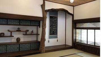 Habitació japonesa tradicional amb sòls de tatami, una estant de fusta amb objectes decoratius, un pergamí penjat i una finestra amb un disseny d'entramat.