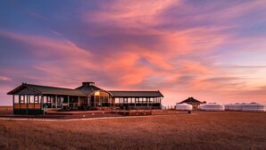 A large, modern building with a covered outdoor area and yurts in the background. - Dream Gobi Lodge (Dalanzadgad)