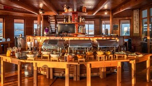 A wooden interior with a central bar area, a large refrigerator, and a television. - Dream Gobi Lodge (Dalanzadgad)