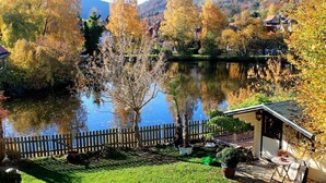A serene lakeside setting with a wooden fence, a small shed, and a grassy area with potted plants. - Lake house with lake view 1  (Ilsenburg (Harz))