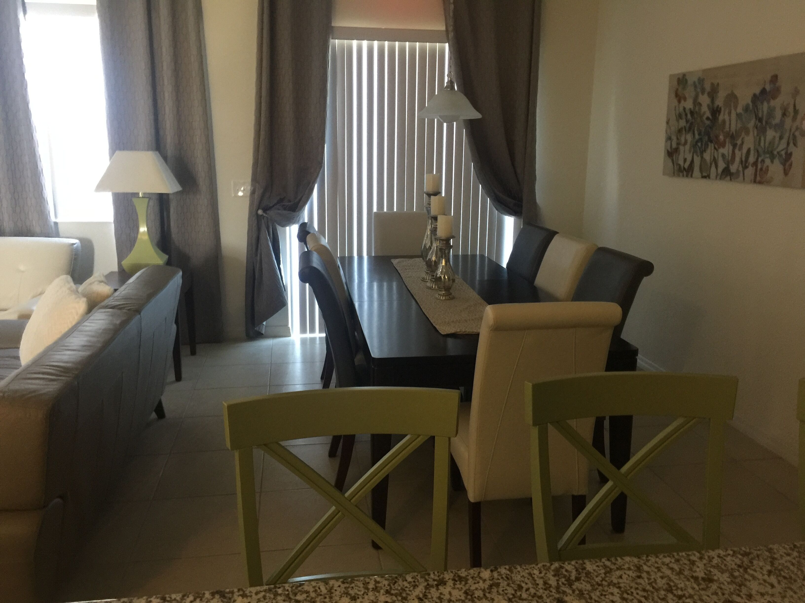 A dining area with a table, chairs, a sofa, and a lamp.