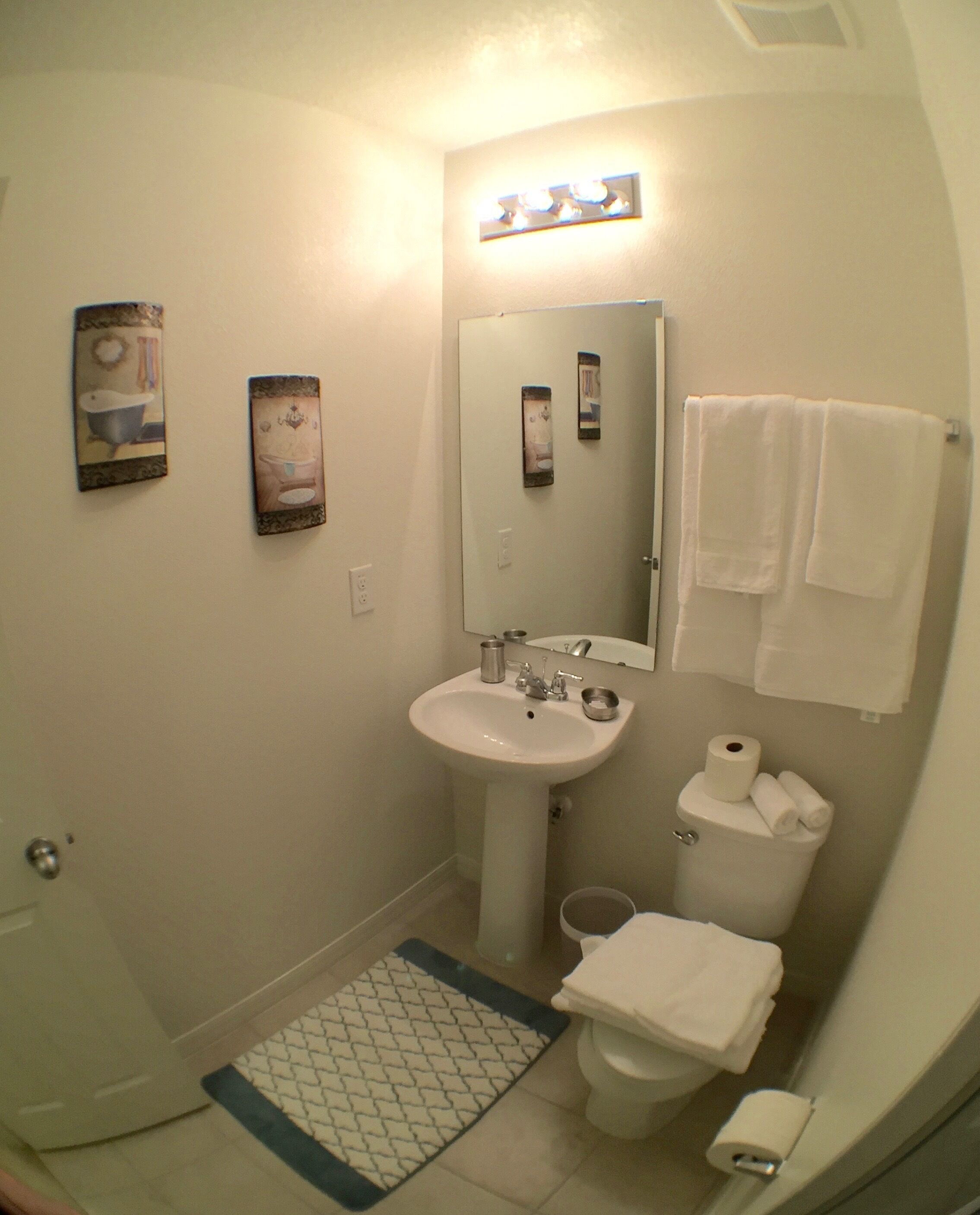 A bathroom with a sink, mirror, toilet, and two towels hanging on the wall.