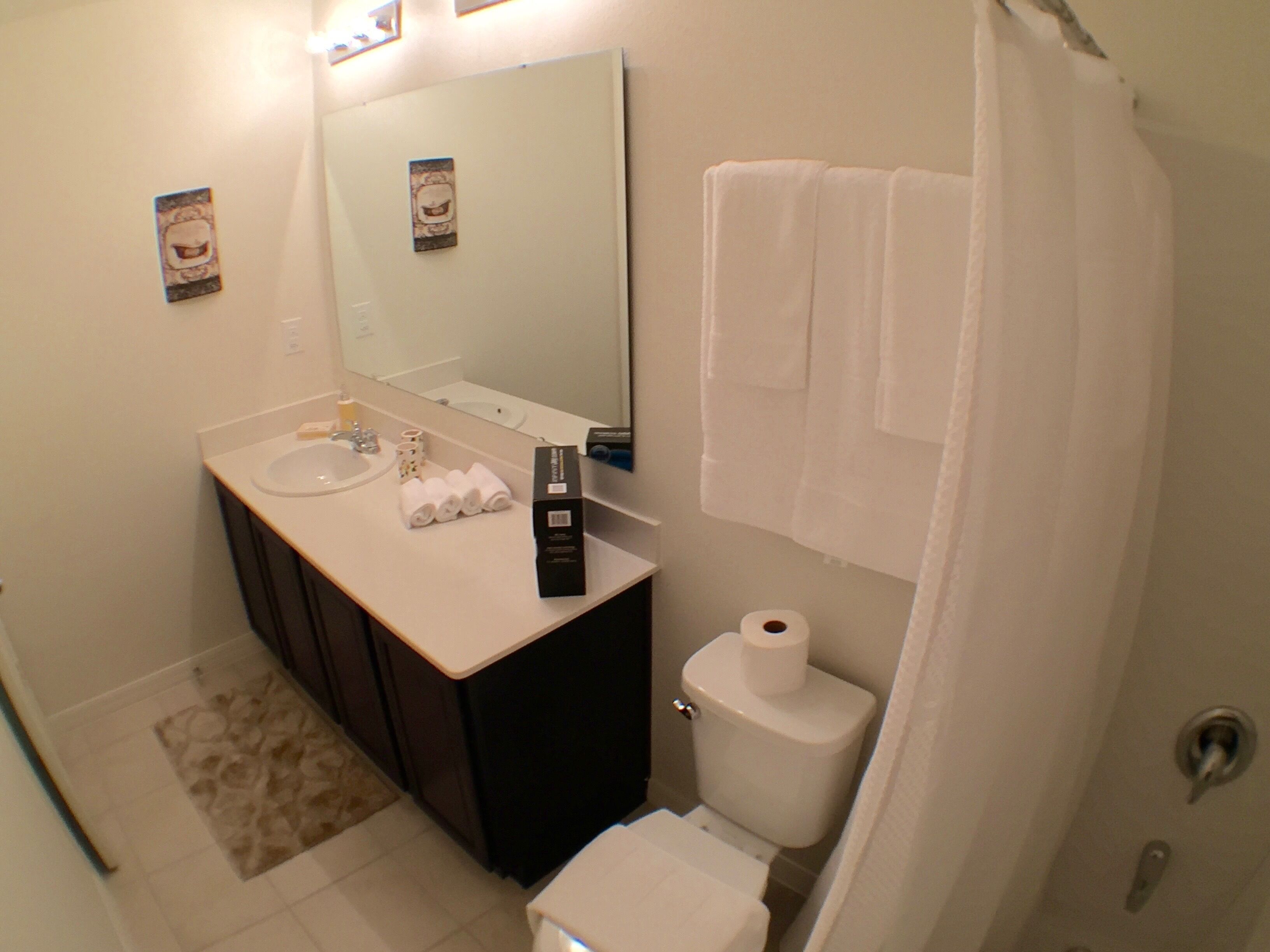 A bathroom with a sink, mirror, toilet, and towels.