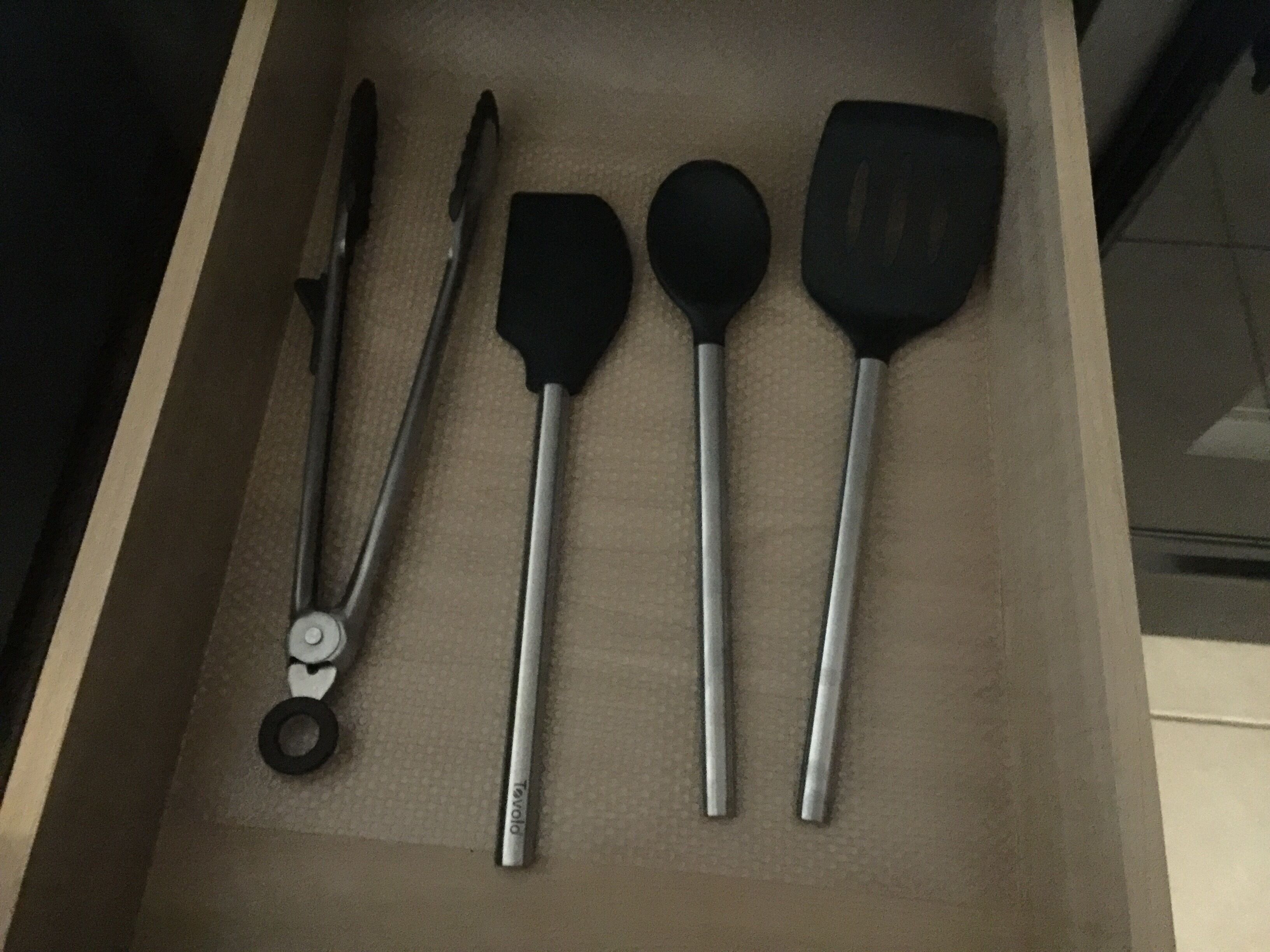 Un tiroir contenant une pince, une spatule et une cuillère.