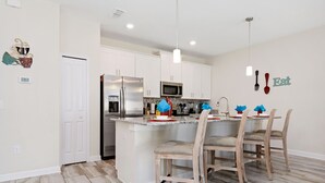 A modern kitchen with white cabinets, stainless steel appliances, and a central island with bar stools.