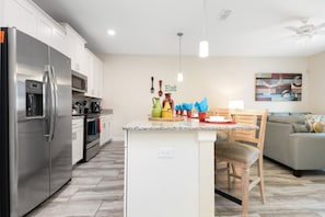 A modern kitchen with white cabinets, a stainless steel refrigerator, and a granite countertop. - Storey Lake 4 Bedrooms near Disney Orlando FL 3079 (Kissimmee)