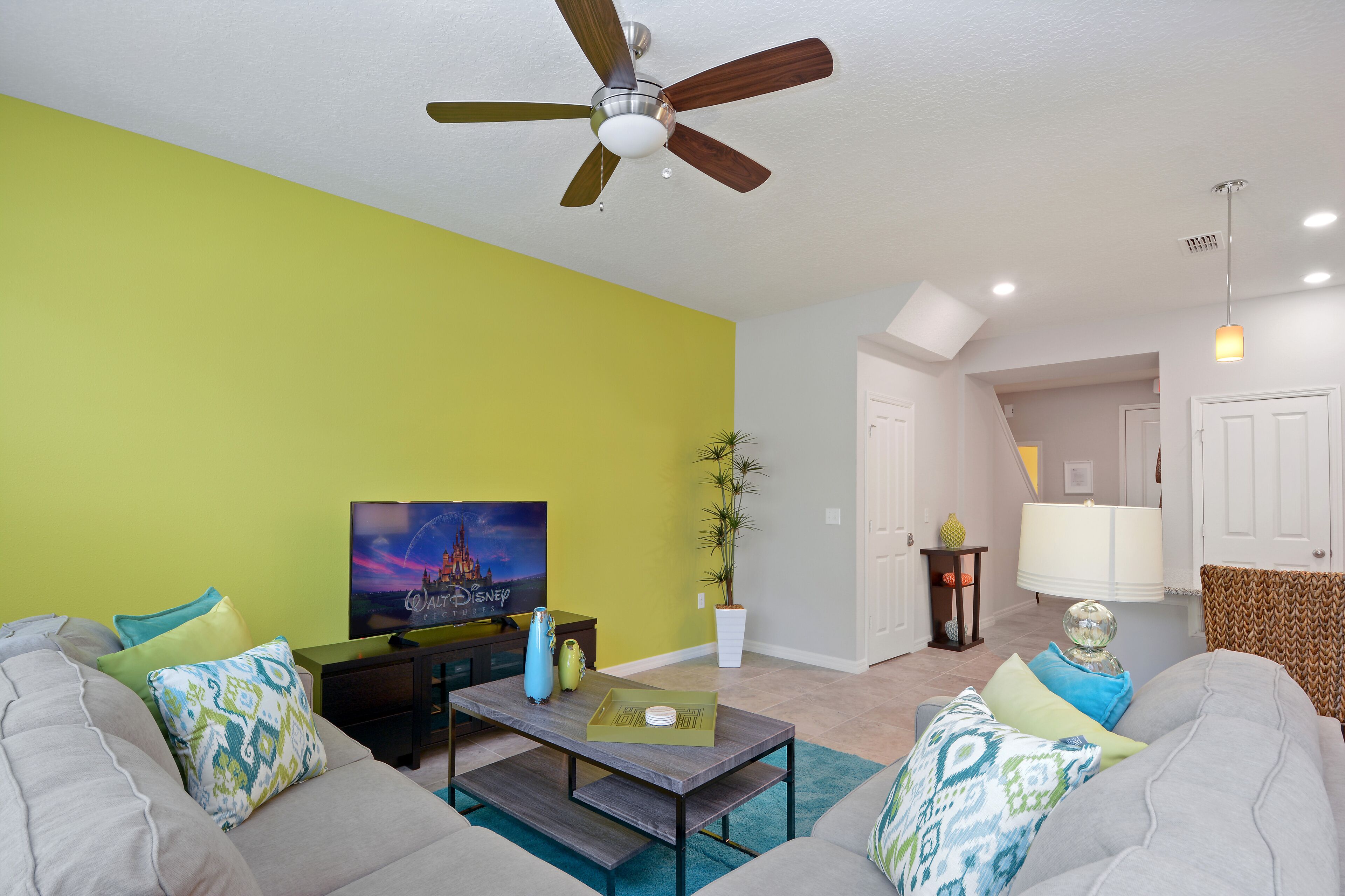 Ein Wohnzimmer mit Deckenventilator, Fernseher, Couchtisch und Sofa.