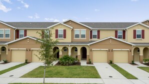 A row of townhouses with a central driveway, garage doors, and small landscaping. - Family Friendly 4 Bedroom close to Disney in Compass Bay Resort 5108 (Kissimmee)