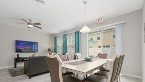 Un espace repas moderne comprenant une table, des chaises et un ventilateur de plafond.