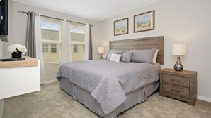 A bedroom with a bed, bedside lamps, a nightstand, a desk, and a window with curtains. - Family Friendly 4 Bedroom close to Disney in Compass Bay Resort 5108 (Kissimmee)