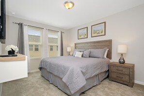 A bedroom with a bed, bedside lamps, a nightstand, a desk, and a window with curtains. - Family Friendly 4 Bedroom close to Disney in Compass Bay Resort 5108 (Kissimmee)