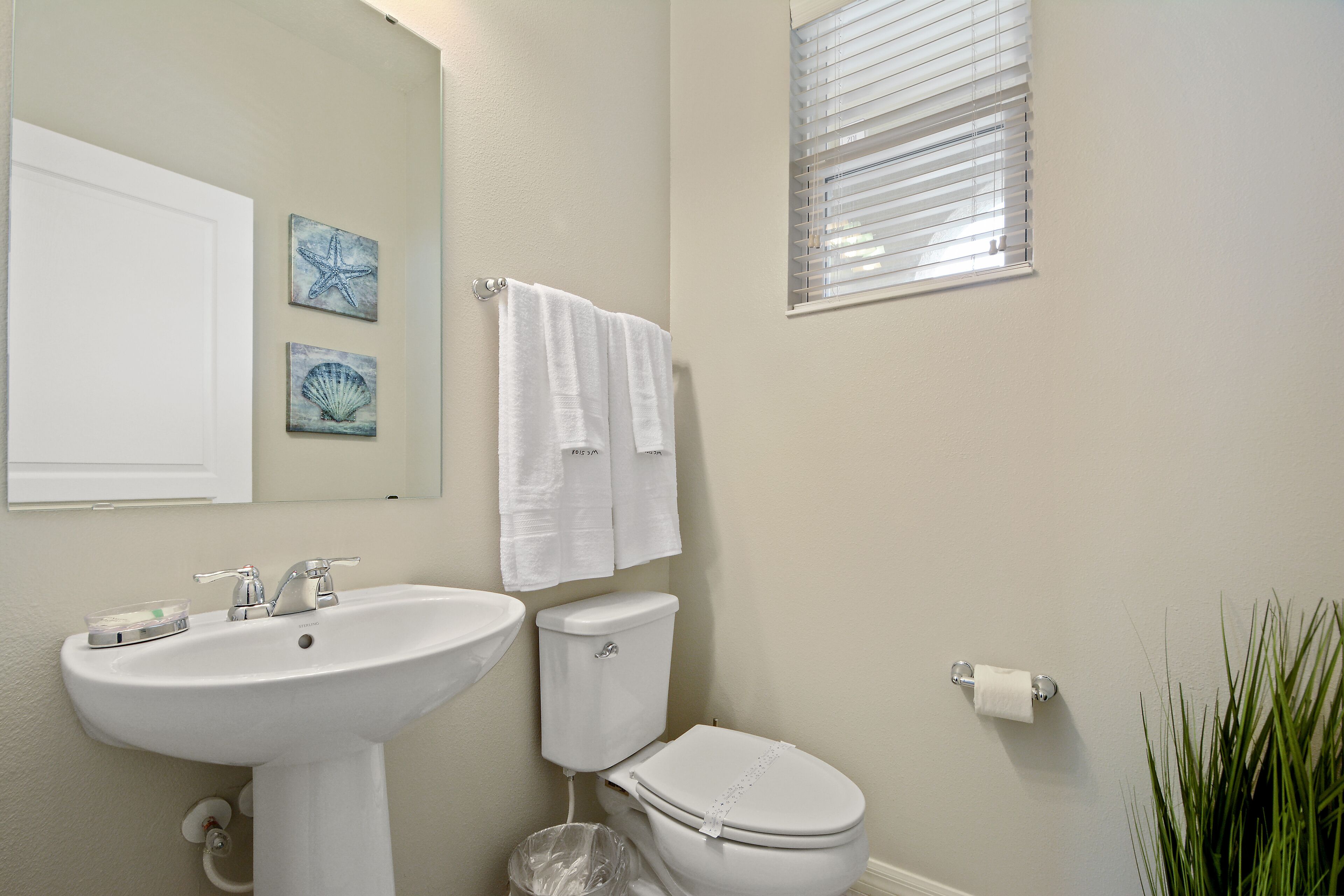 A bathroom with a sink, toilet, and a window with blinds.