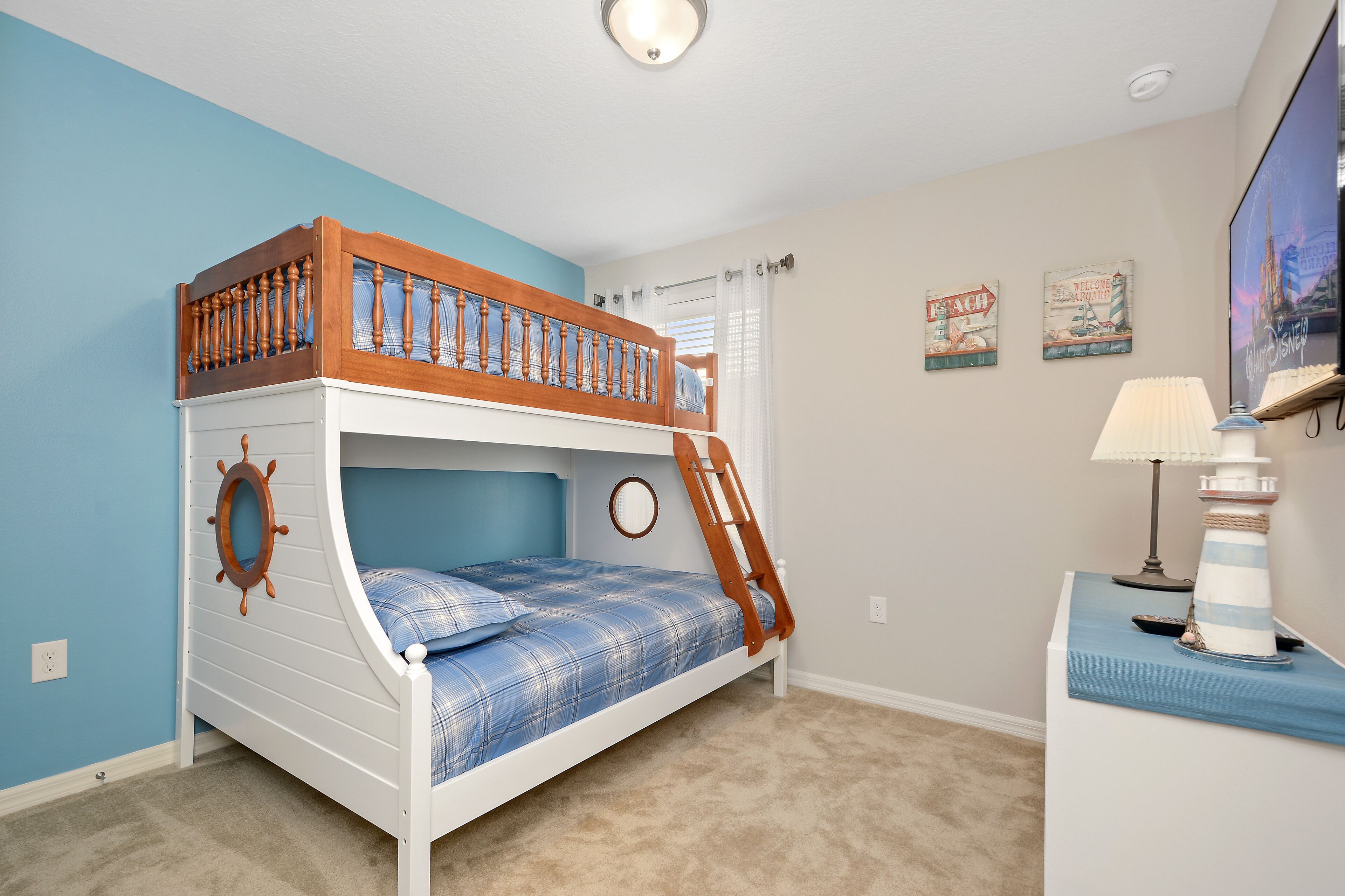 A bunk bed with a wooden ladder, a circular wall decoration, and a lamp on a side table.