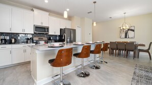 A modern kitchen with white cabinets, stainless steel appliances, and a central island with bar stools.