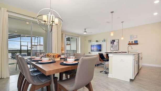 A modern kitchen with a central island, a dining area with a wooden table and chairs, and a large window overlooking a balcony.