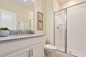 A bathroom with a white sink, vanity, toilet, and a glass-enclosed shower. - Charming 4Bd w/ Pool @ Storey Lake Resort Orlando 4861 (Kissimmee)