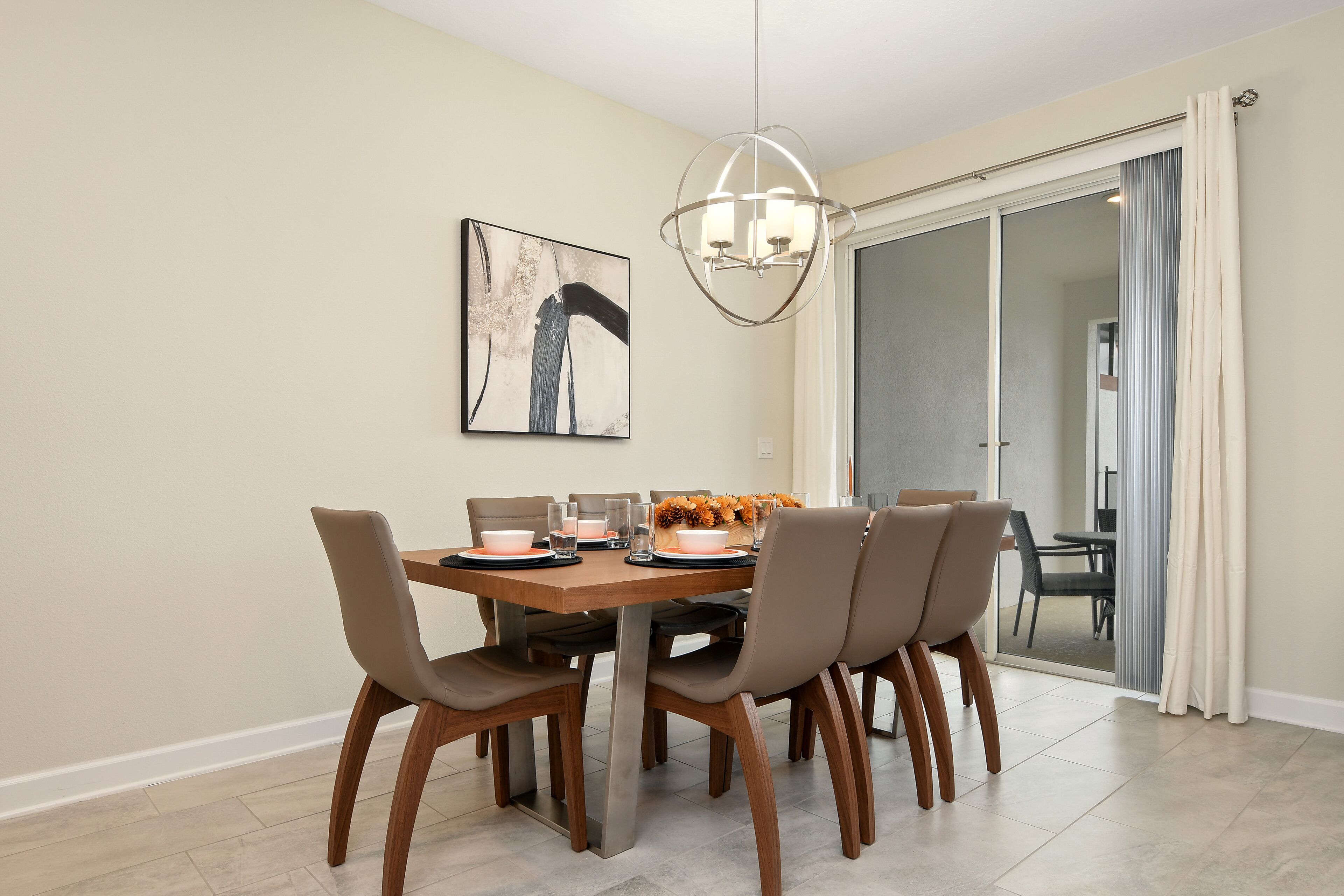 Un comedor con una mesa de madera, seis sillas y una lámpara moderna.
