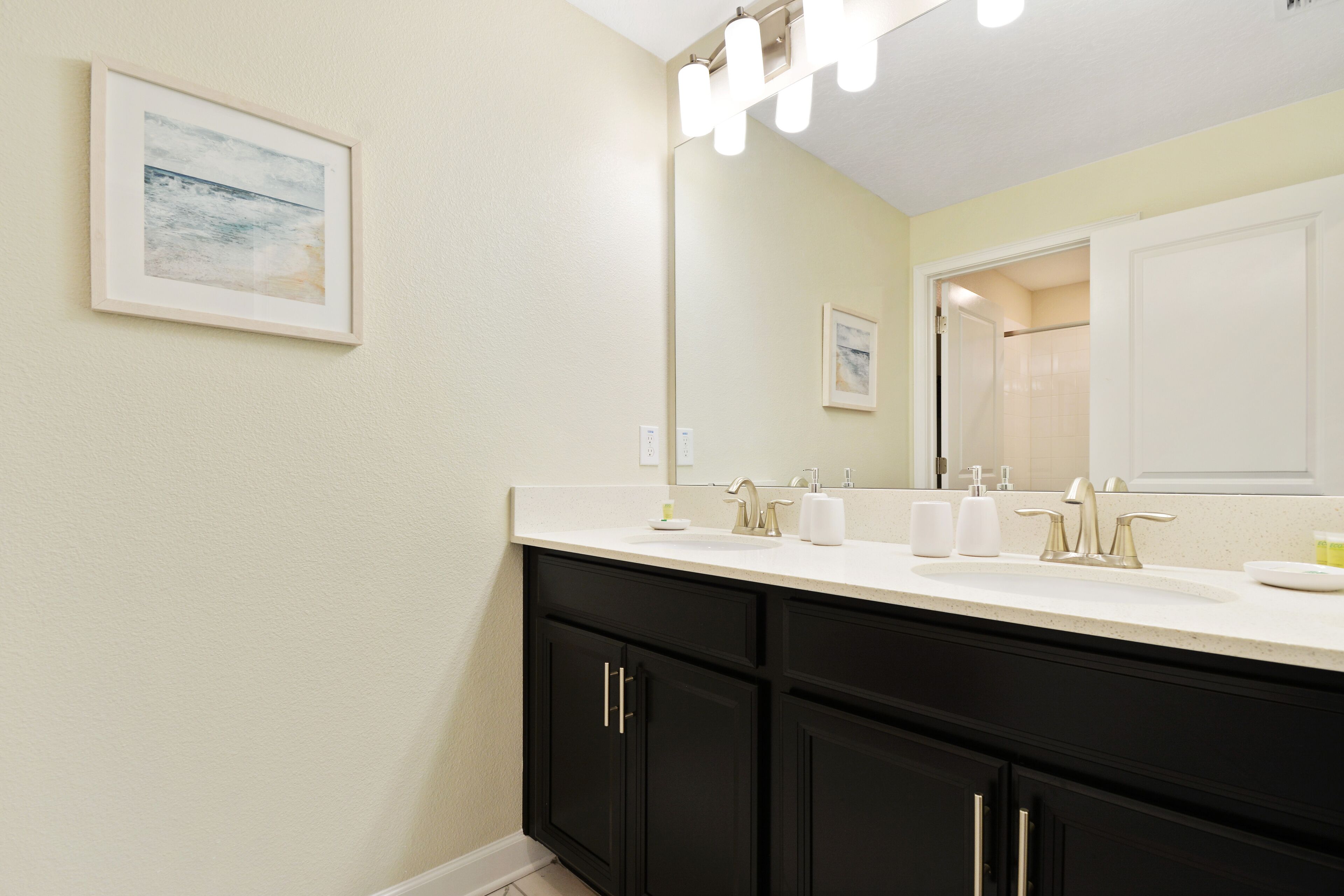 Une salle de bain avec un double vasque, des meubles noirs et un grand miroir.