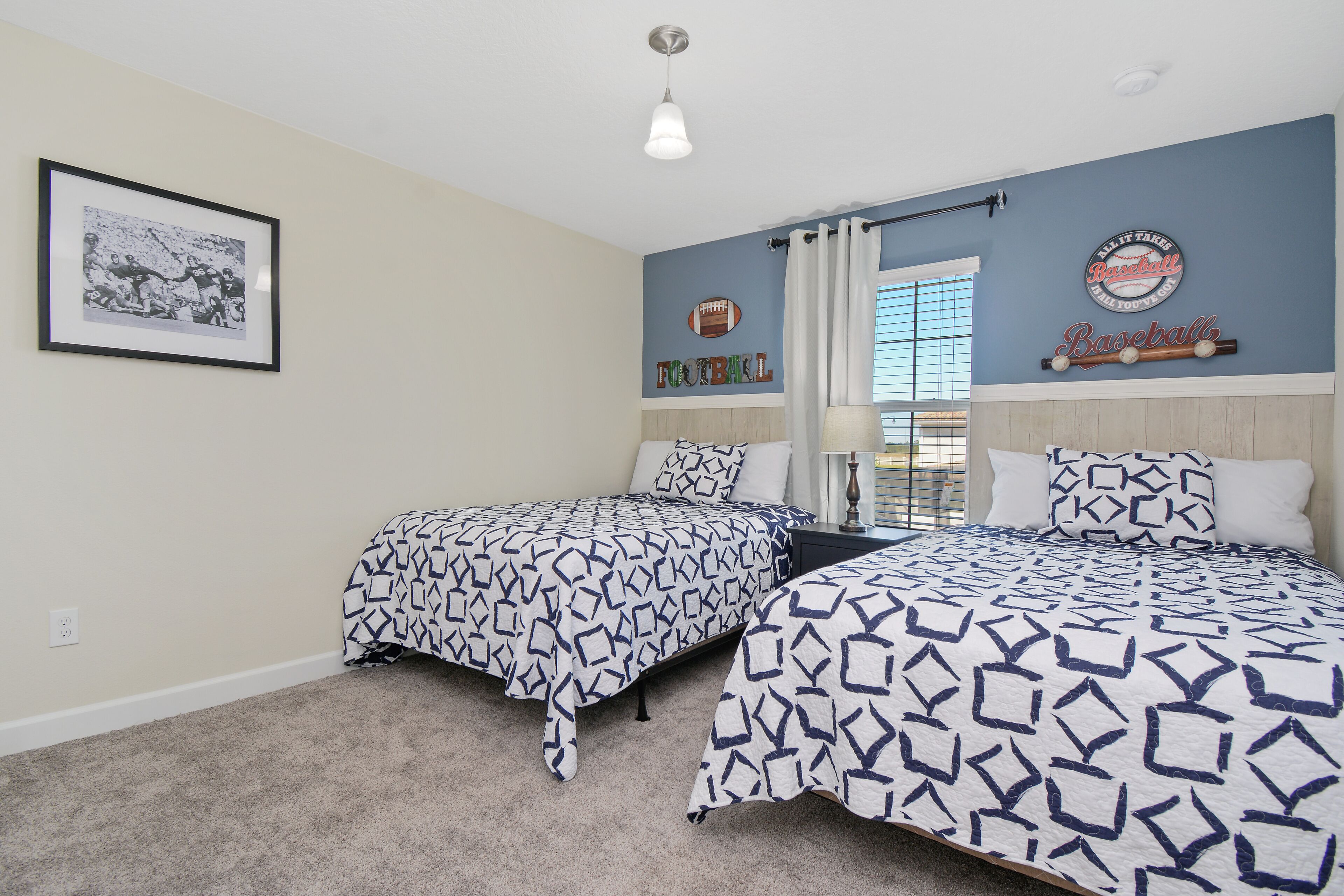 A bedroom with two beds, a framed photo on the wall, and a baseball-themed decor.