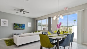 A modern dining area with a white sofa, a dining table, and chairs. - 4 Bd Sleeps 10 w/ GameRoom Close to Disney 5147 (Kissimmee)