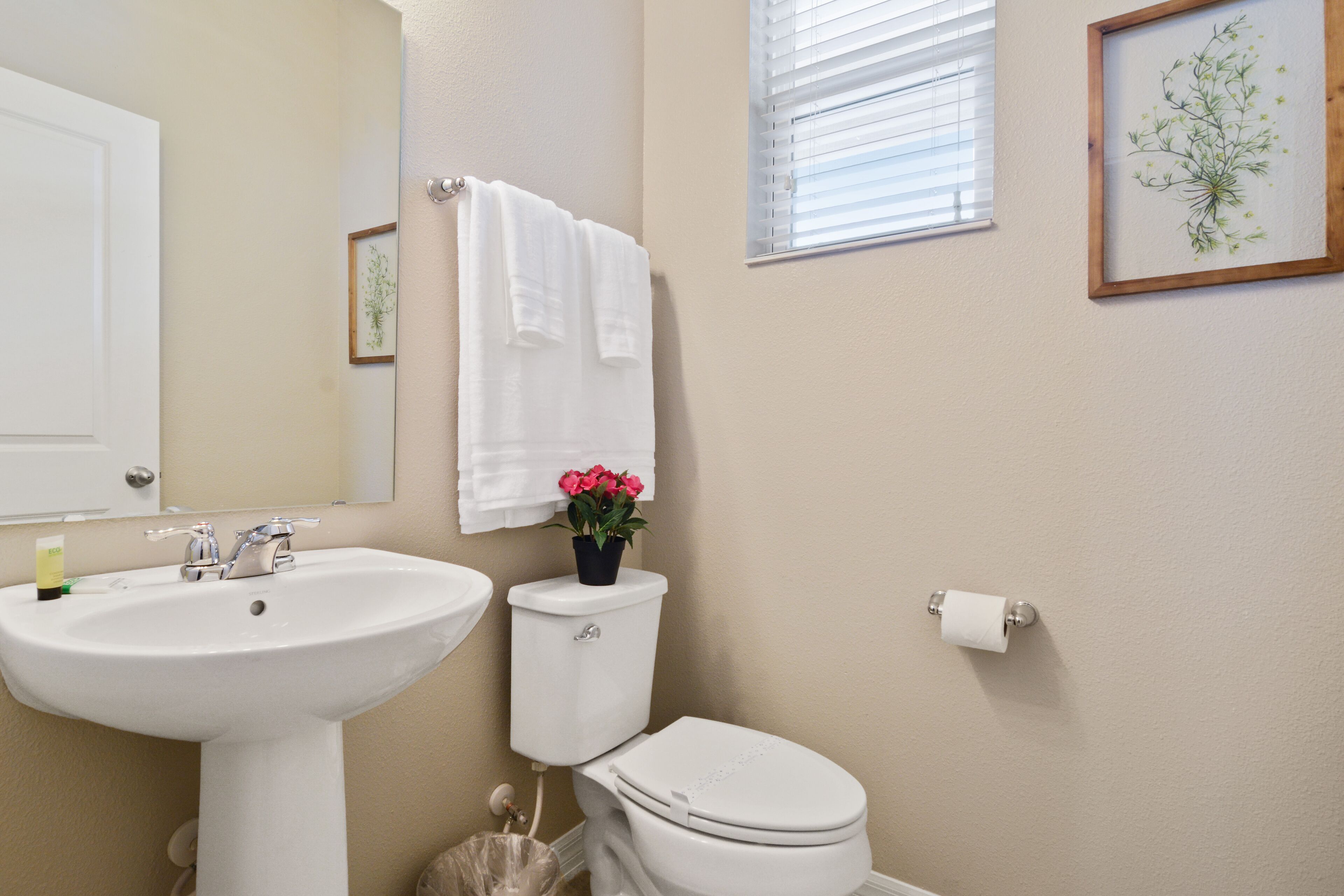 Une salle de bain avec un lavabo blanc, des toilettes et un tableau encadré au mur.